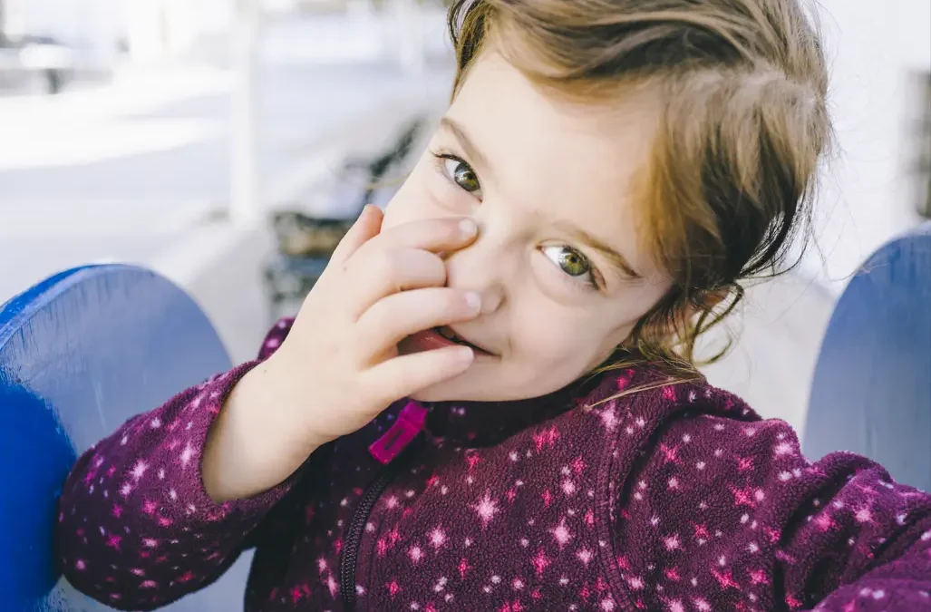 Bambina sorride mostrando i denti da latte: l'importanza di prevenire carie e proteggere il microbioma orale nei primi anni di vita.