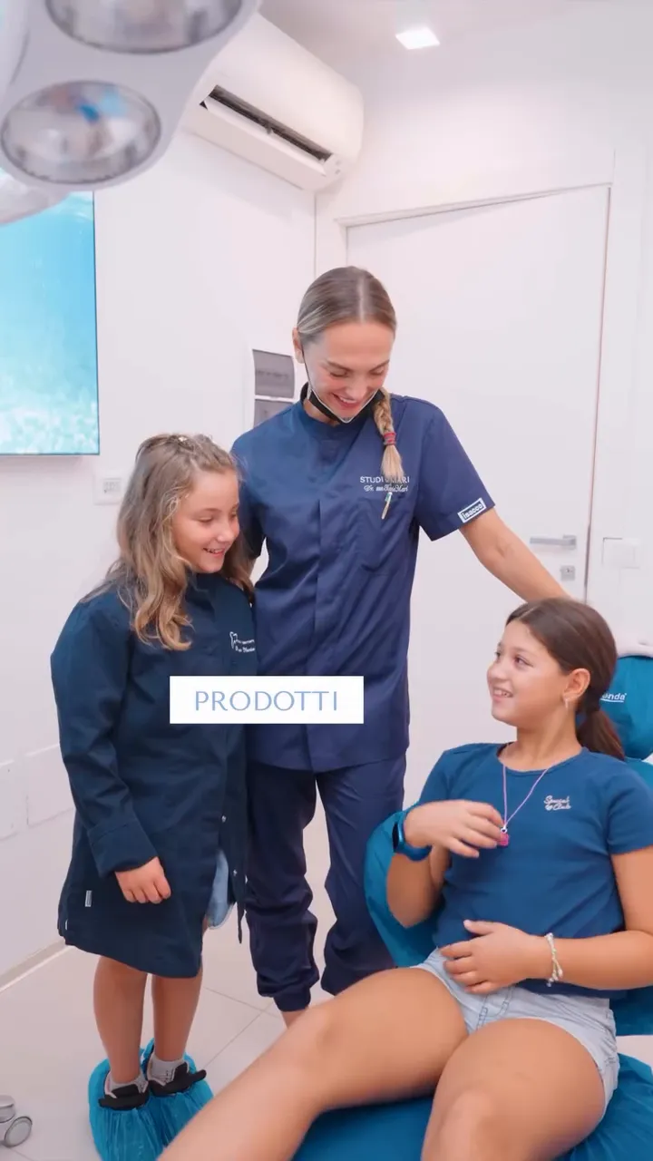 Prodotti per la prevenzione carie nei bambini: consigli del dentista pediatrico Dentista pediatrico mostra a due giovani pazienti i prodotti per la prevenzione orale e il mantenimento del microbioma sano.